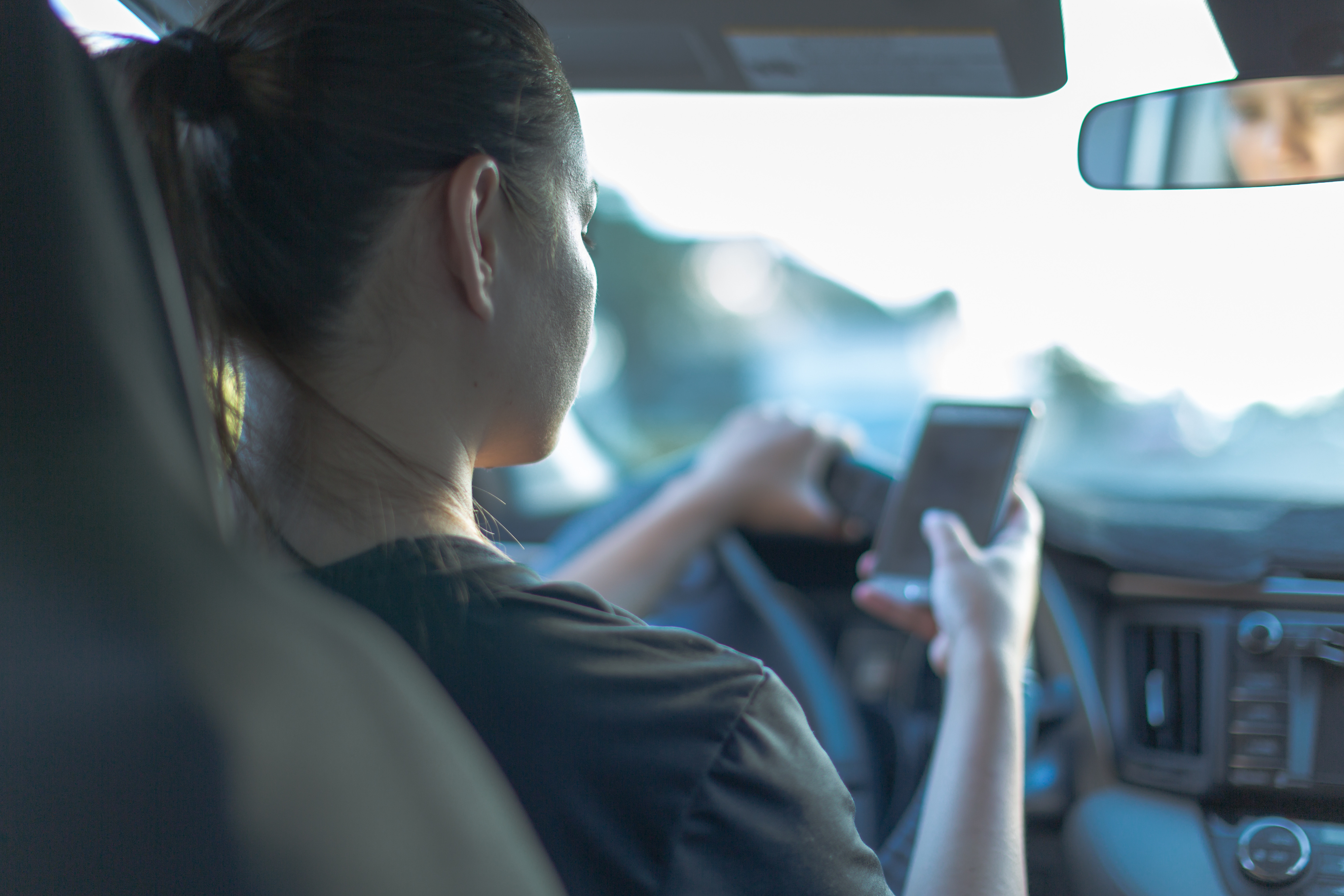 Woman looking down at her cellphone while driving.
